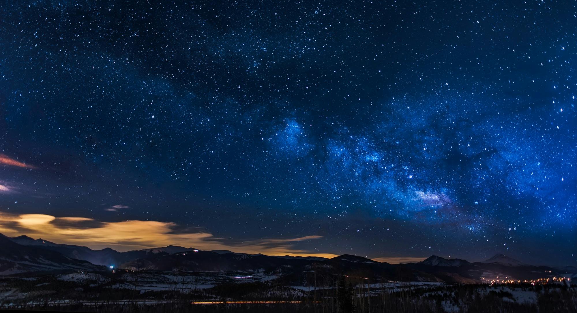 Bright stars in the dark blue sky, beyond a view of mountains